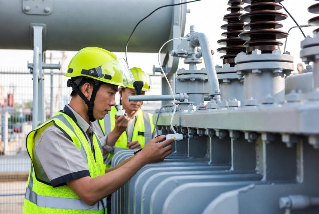 Engineer using an acoustic sensor to locate partial discharge inside a power transformer.
