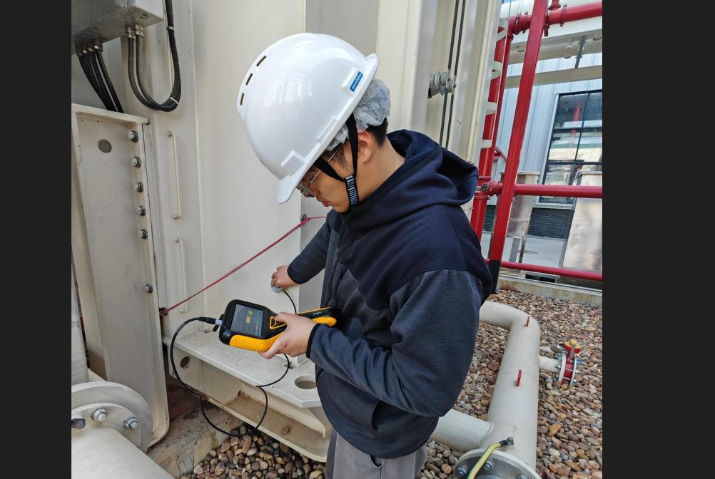 Engineers performing partial discharge testing on a power transformer using portable monitoring equipment.